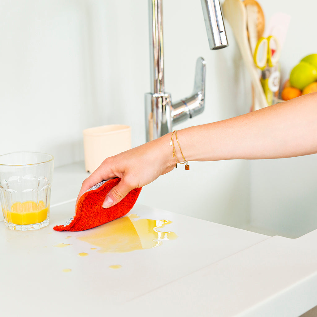 Eponge lavable rouge essuyant du jus d'orange