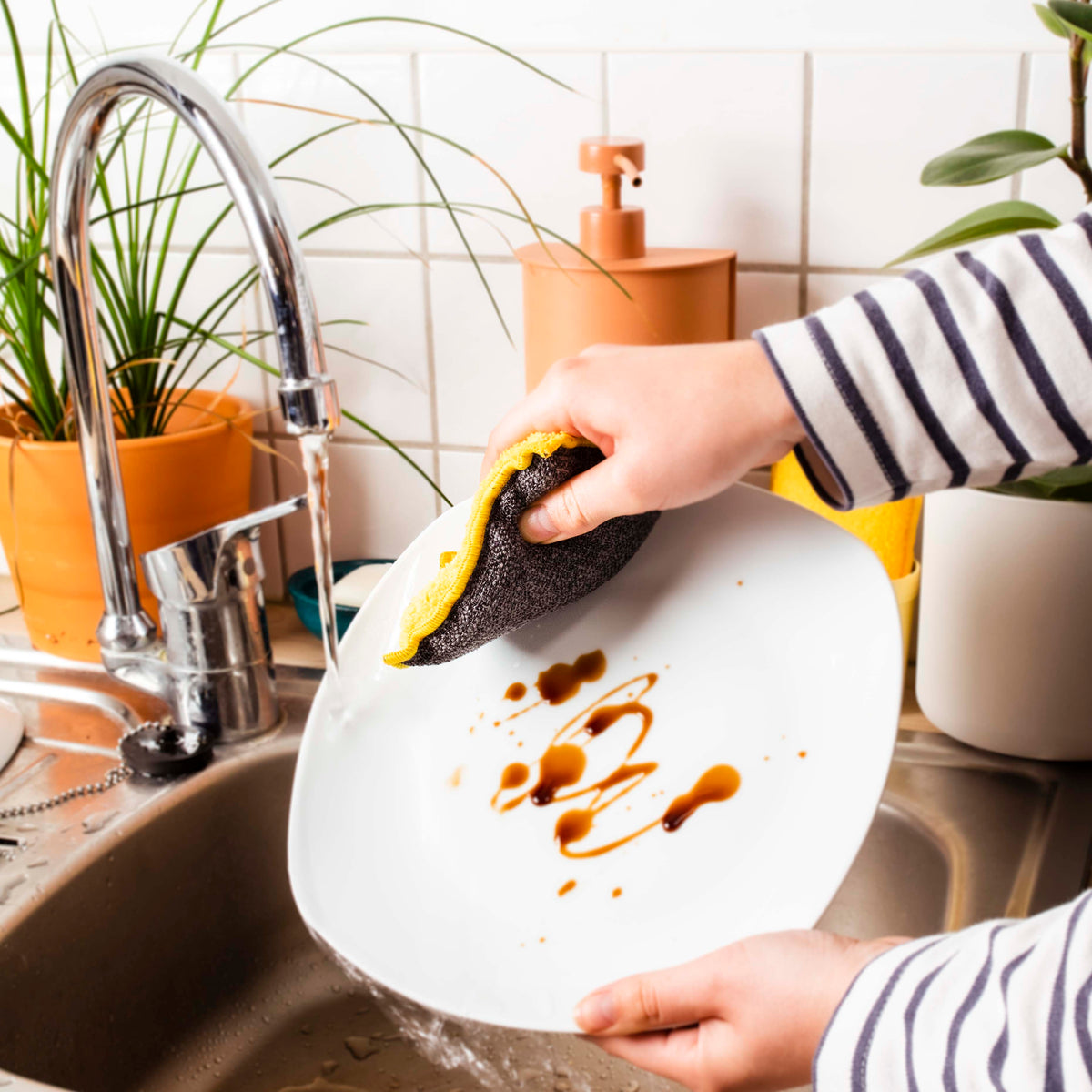 Eponge lavable jaune nettoyant une assiette